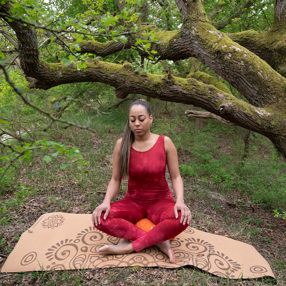 Een meisje mediteert in het bos op de kurk yogamat_2 een vrouw die geniet van bemiddeling in de natuur