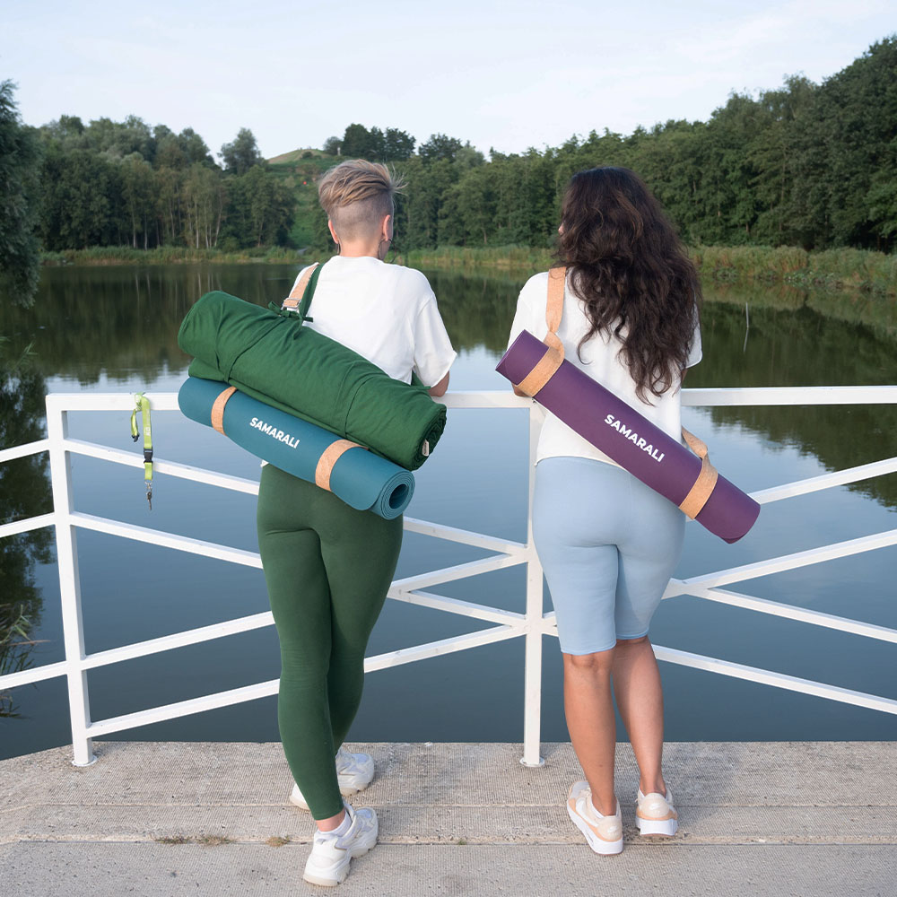 Cotton mat - forest green_10 two female standing facing on the river. They are holding two types yoga mats - one is cotton mat and another is natural rubber mat