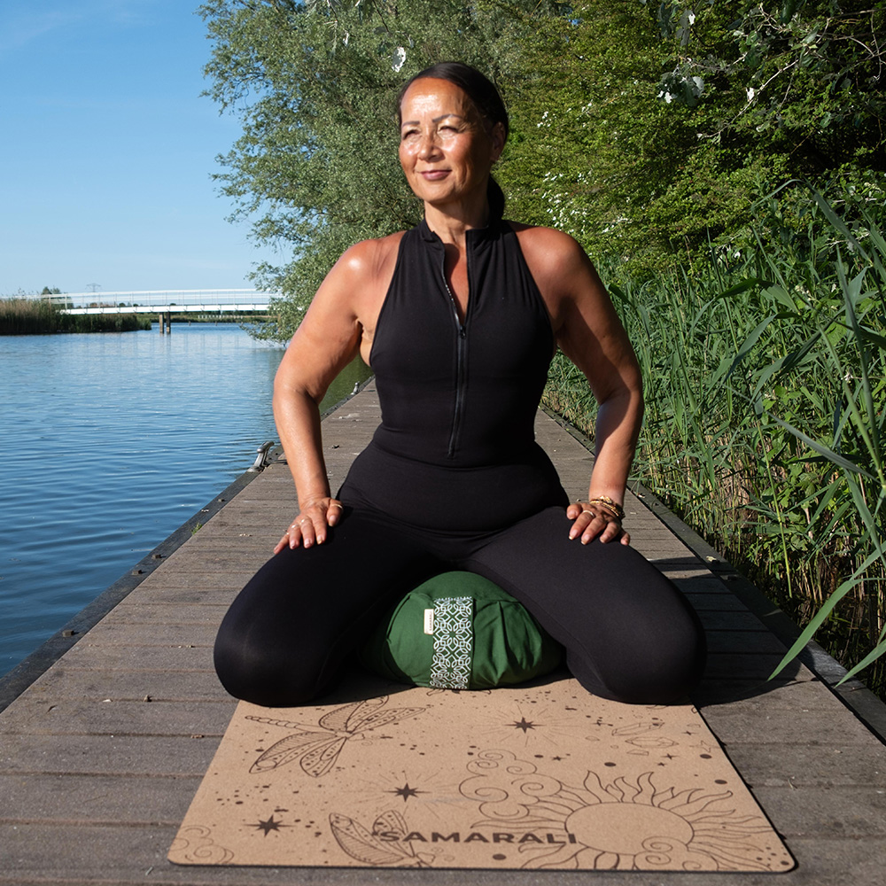 A female doing meditation next to the river sitting on the meditation cushion zafu and the yoga mat Cosmic Harmony Cork Yoga Mat cork yoga mat