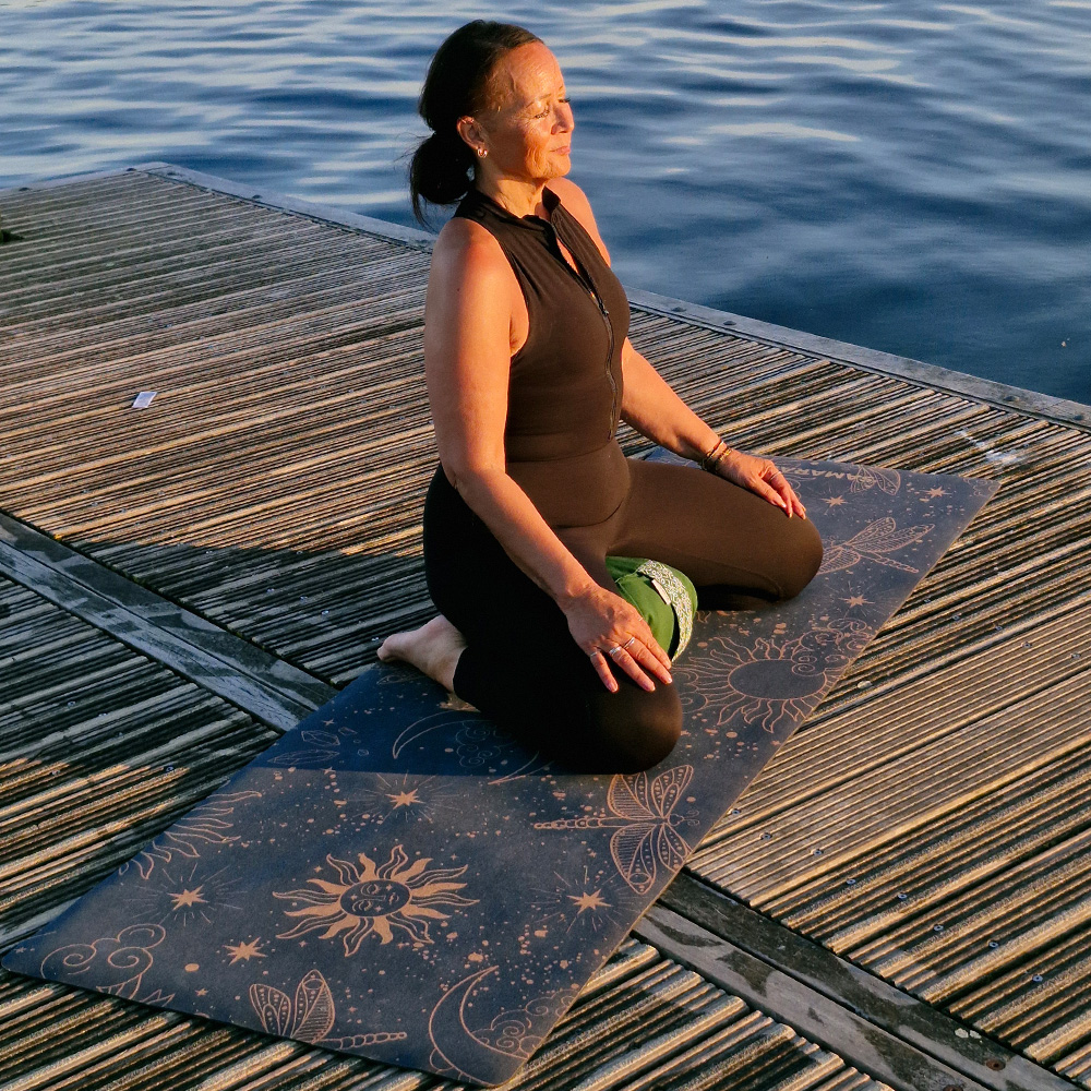 A female meditating sitting on meditation cushion zafu and a cork yoga mat 4 Cosmic Harmony Cork Yoga Mat cork yoga mat