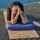 a female exercising on the cork yoga mat using blue yoga bolster Cosmic Harmony Cork Yoga Mat cork yoga mat