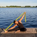 a female exercising on the yoga mat using the yoga straps in green Cosmic Harmony Cork Yoga Mat cork yoga mat