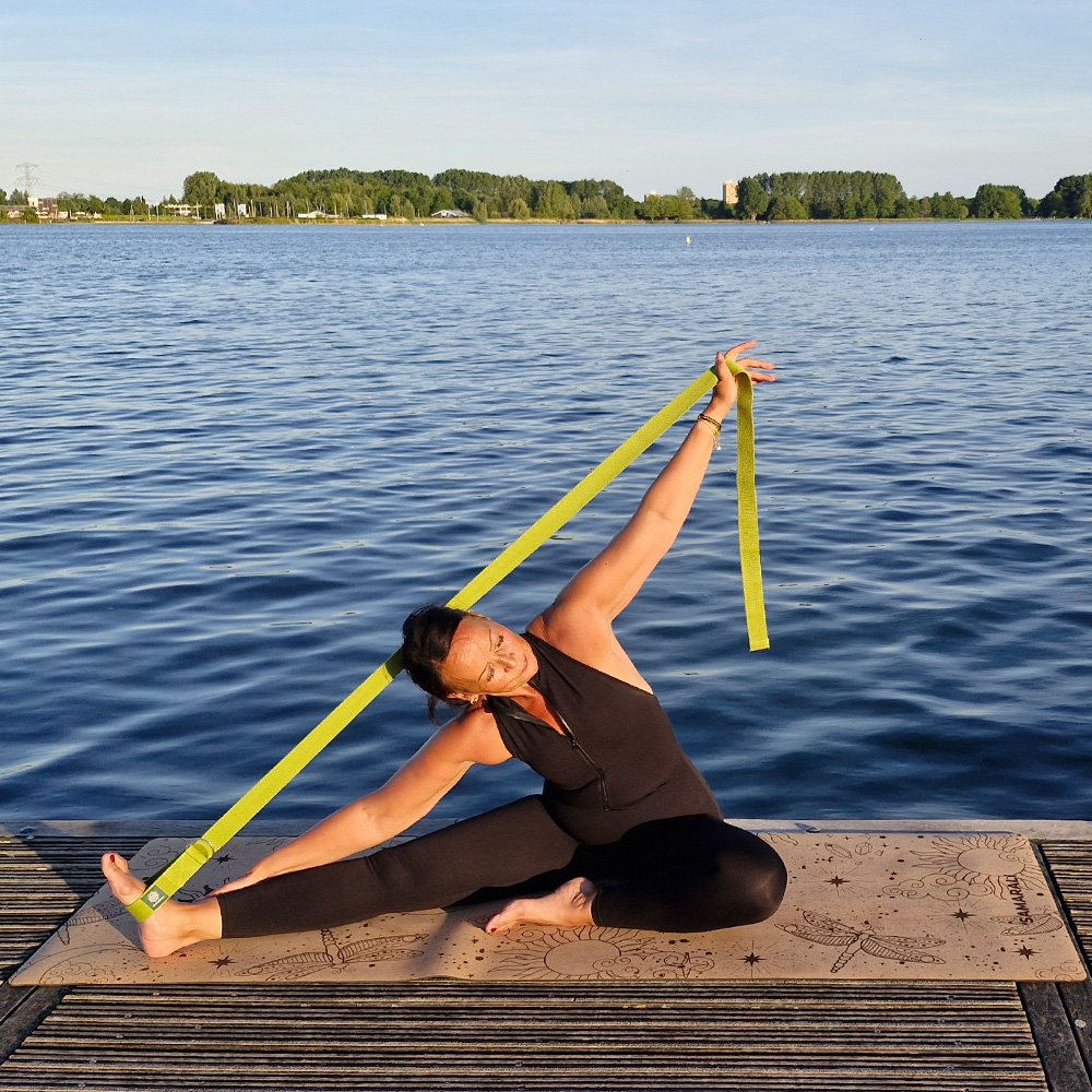a female exercising on the yoga mat using the yoga straps in green Cosmic Harmony Cork Yoga Mat cork yoga mat