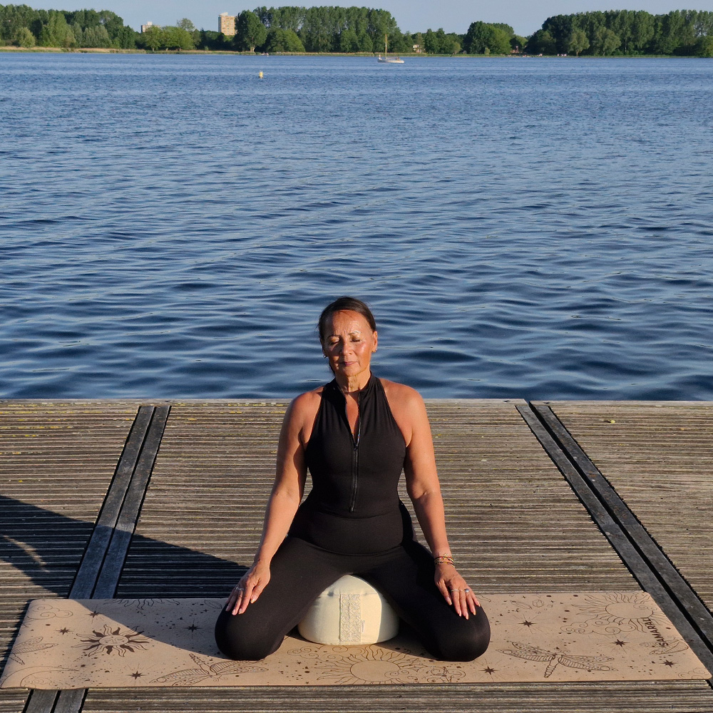 a female meditating on the cork yoga mat and the round meditation cushion Cosmic Harmony Cork Yoga Mat cork yoga mat